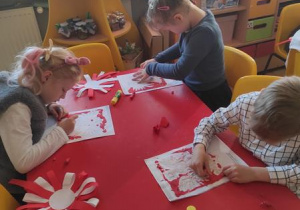 Dzieci wyklejają plasteliną godło Polski